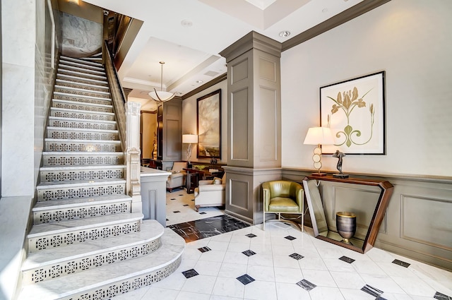 stairway with decorative columns, a raised ceiling, and tile patterned flooring