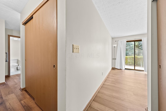 hallway featuring a textured ceiling and light wood-type flooring