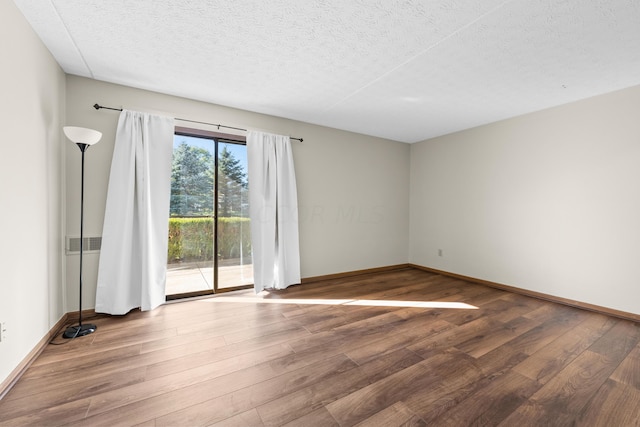 unfurnished room with a textured ceiling and hardwood / wood-style flooring