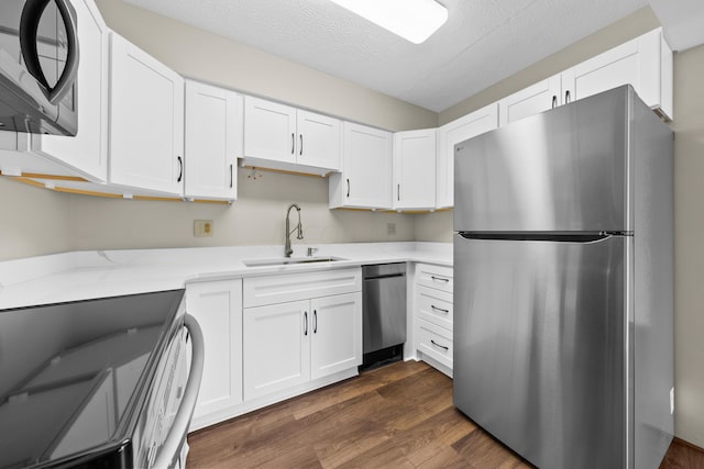 kitchen featuring dark hardwood / wood-style flooring, a textured ceiling, stainless steel appliances, sink, and white cabinetry