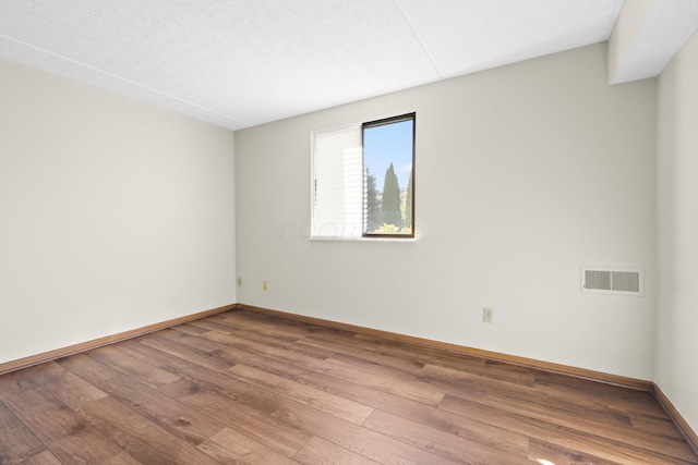 unfurnished room featuring hardwood / wood-style floors and a textured ceiling