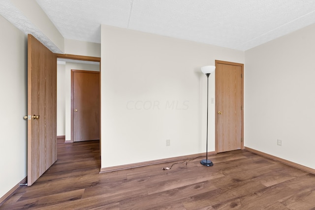 empty room with dark hardwood / wood-style flooring and a textured ceiling