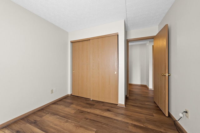 unfurnished bedroom featuring a textured ceiling, a closet, and dark wood-type flooring