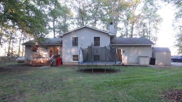 rear view of property featuring a lawn and a trampoline