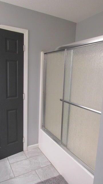 bathroom featuring tile patterned floors and combined bath / shower with glass door