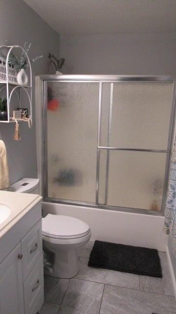 full bathroom featuring tile patterned floors, vanity, toilet, and enclosed tub / shower combo