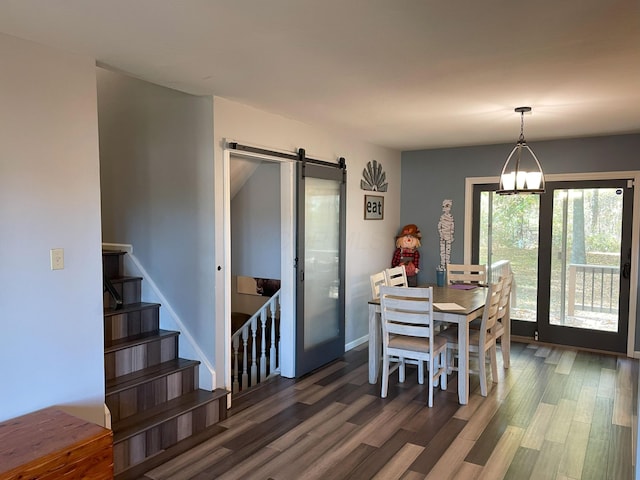 dining room with a chandelier, a barn door, and dark hardwood / wood-style floors