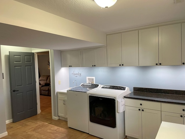 laundry area with washer and clothes dryer, cabinets, a textured ceiling, and sink