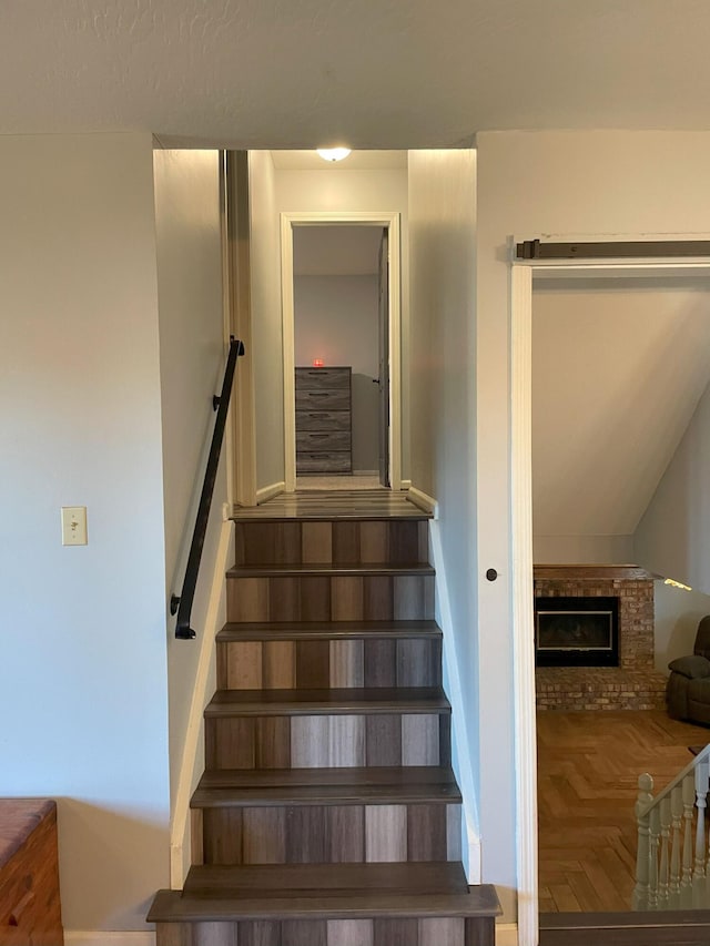 stairway with a fireplace and parquet floors