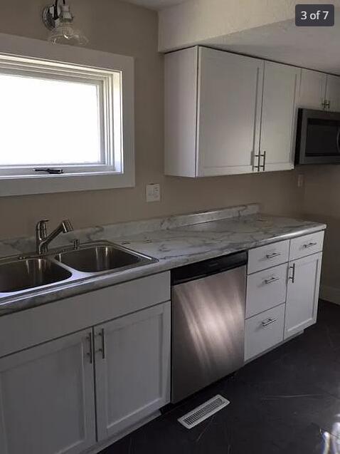 kitchen with white cabinets, light stone counters, sink, and stainless steel appliances