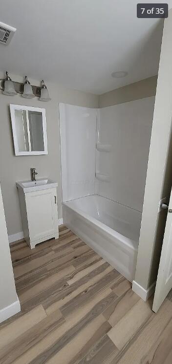 bathroom featuring hardwood / wood-style flooring, vanity, and washtub / shower combination