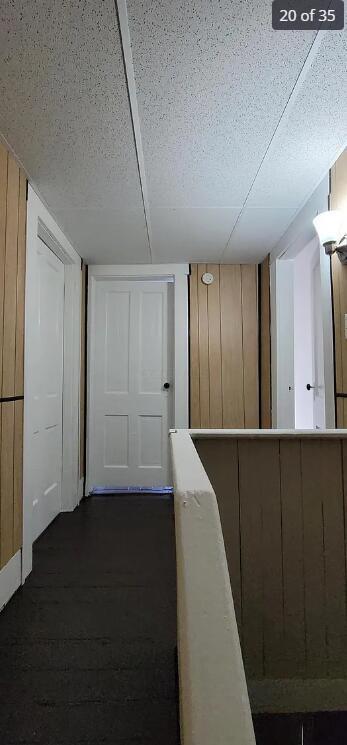 hallway with dark hardwood / wood-style flooring and wood walls