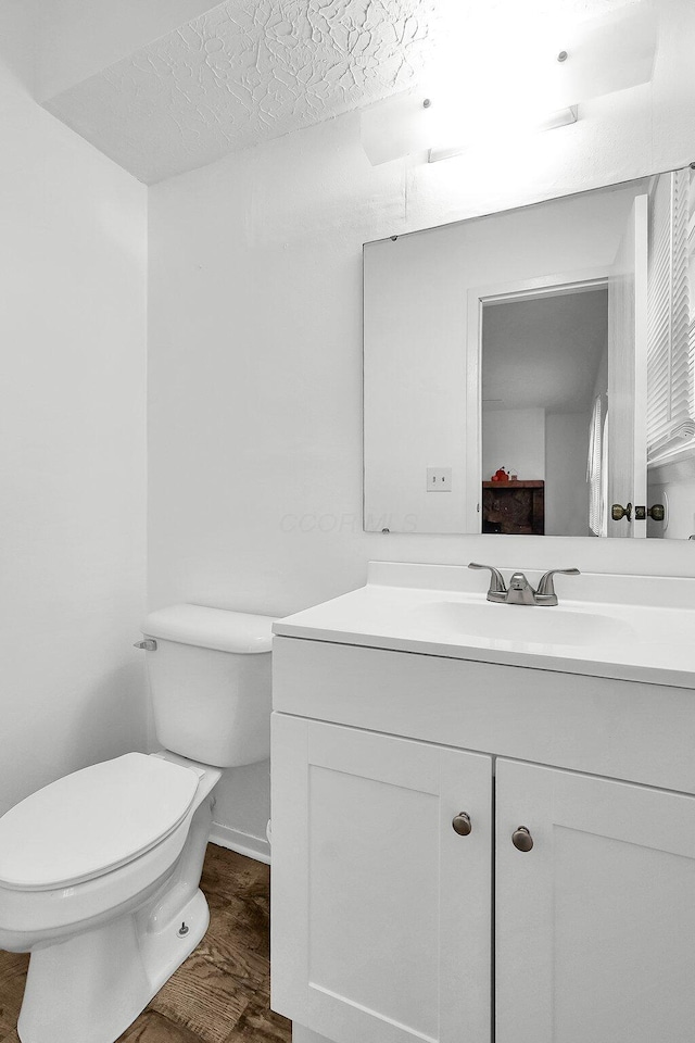 bathroom with hardwood / wood-style flooring, vanity, toilet, and a textured ceiling