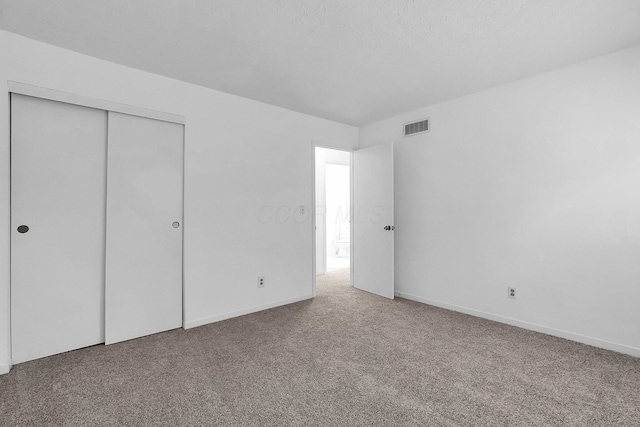 unfurnished bedroom with carpet, a textured ceiling, and a closet