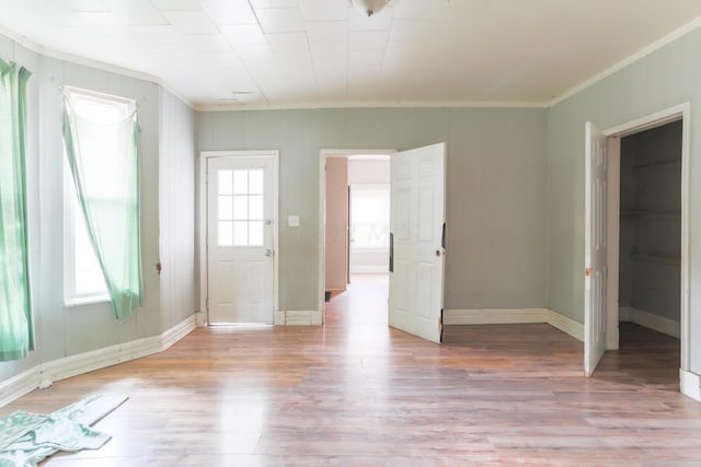 entryway featuring light wood-type flooring, crown molding, and a healthy amount of sunlight