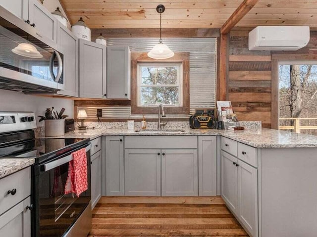 kitchen with a wealth of natural light, a wall unit AC, sink, and appliances with stainless steel finishes