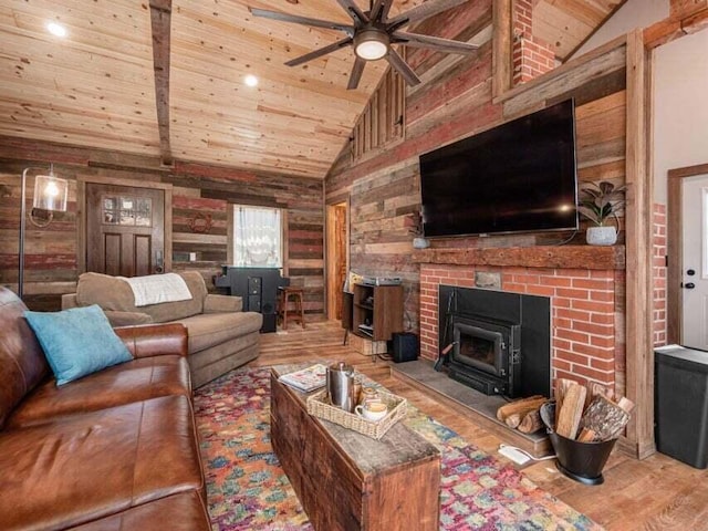 living room with a wood stove, wood walls, ceiling fan, and hardwood / wood-style flooring