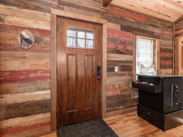 entryway with wooden walls, hardwood / wood-style floors, and vaulted ceiling