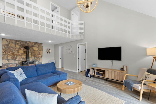 living room featuring hardwood / wood-style floors, an inviting chandelier, high vaulted ceiling, and a wood stove