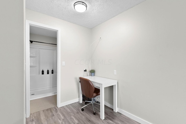 home office with light wood-type flooring and a textured ceiling