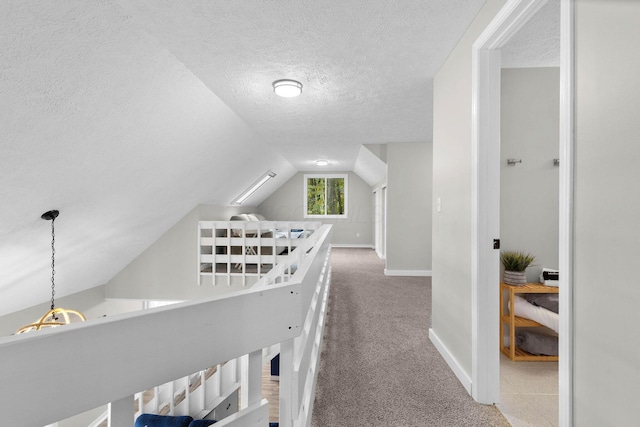 hall with carpet, a textured ceiling, and vaulted ceiling