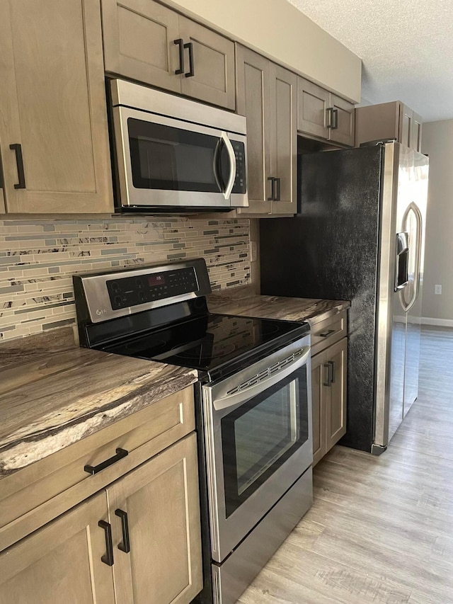 kitchen with stainless steel appliances, a textured ceiling, wood counters, decorative backsplash, and light wood-type flooring