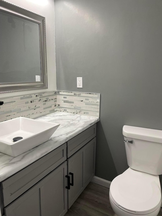 bathroom featuring hardwood / wood-style flooring, vanity, toilet, and backsplash