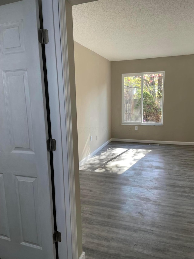 empty room with dark hardwood / wood-style floors and a textured ceiling