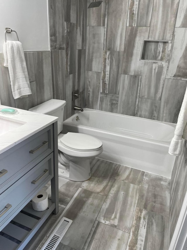 full bathroom with toilet, tile walls, vanity, and shower / bathing tub combination