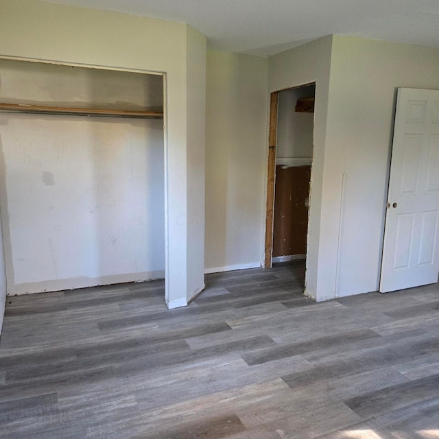 unfurnished bedroom with a closet, wood finished floors, and baseboards