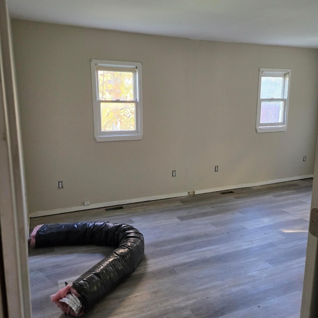 unfurnished room with visible vents, baseboards, and wood finished floors