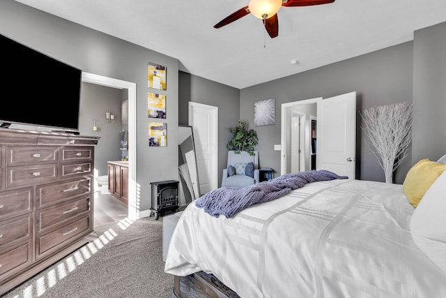 carpeted bedroom featuring a wood stove and ceiling fan