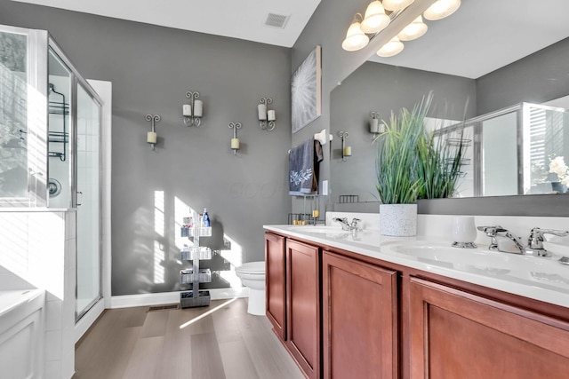 bathroom with hardwood / wood-style floors, vanity, toilet, and a shower with shower door