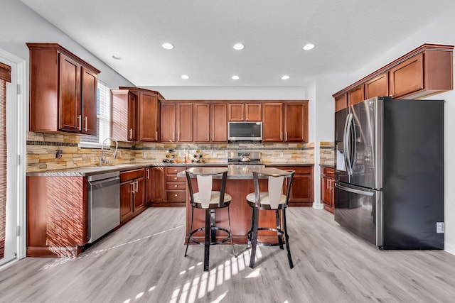 kitchen featuring a kitchen island, sink, stainless steel appliances, and light hardwood / wood-style flooring