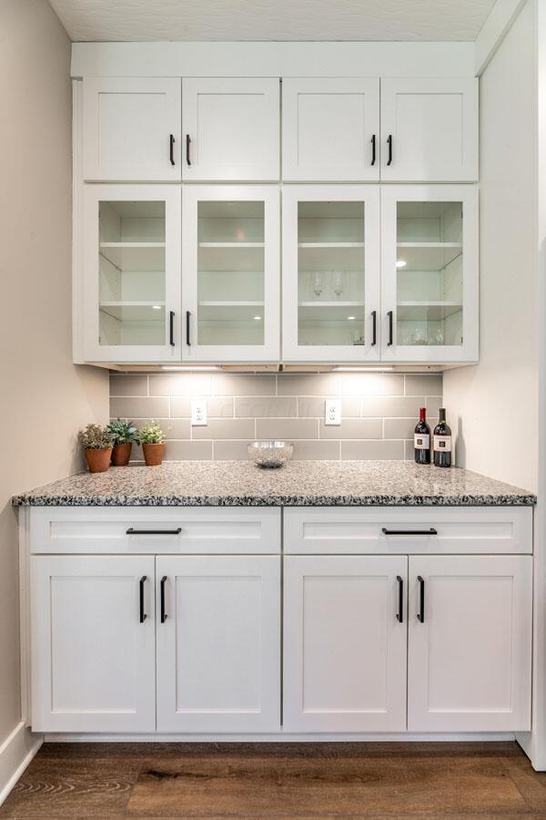 bar with backsplash and white cabinetry