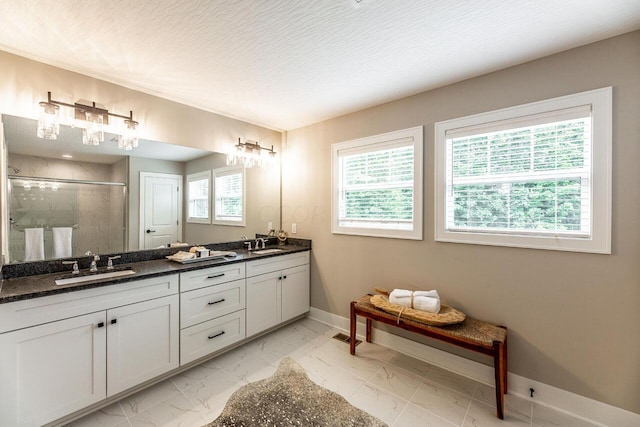 bathroom with plenty of natural light, vanity, a shower with door, and a textured ceiling