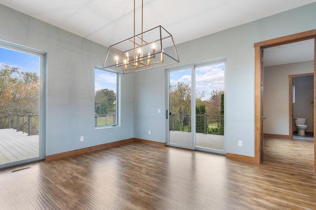 unfurnished dining area featuring wood-type flooring and an inviting chandelier