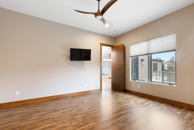 empty room featuring ceiling fan with notable chandelier and light hardwood / wood-style flooring