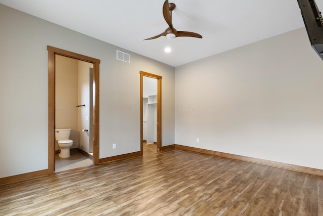 unfurnished bedroom featuring ceiling fan, a spacious closet, connected bathroom, light hardwood / wood-style floors, and a closet