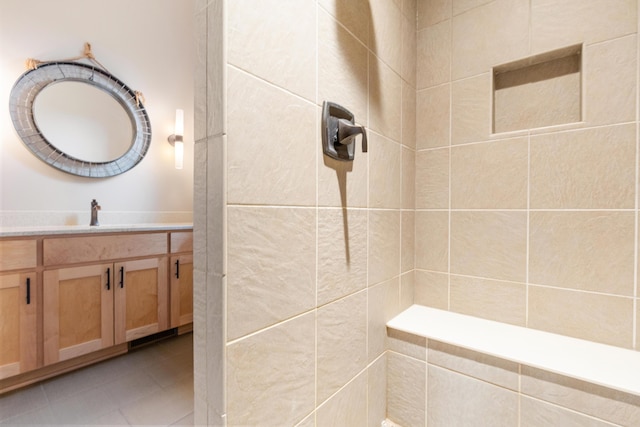 bathroom with a tile shower, vanity, and tile patterned floors