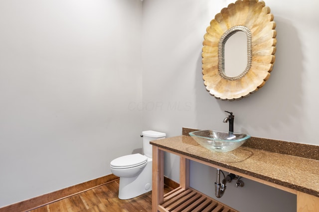 bathroom featuring wood-type flooring, toilet, and sink