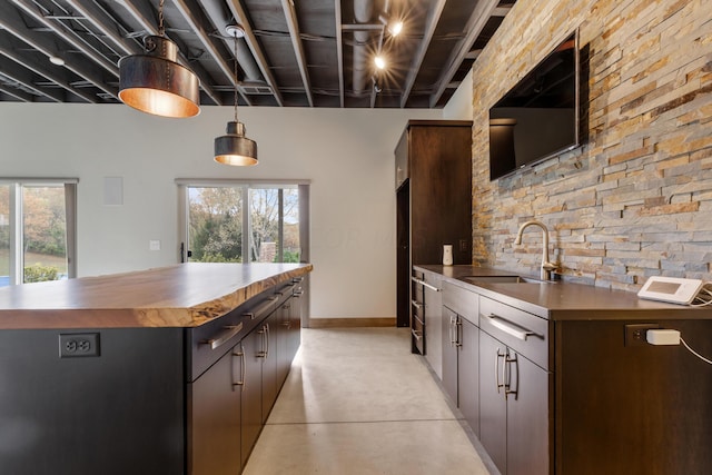 kitchen with decorative light fixtures, a center island, dark brown cabinetry, and sink