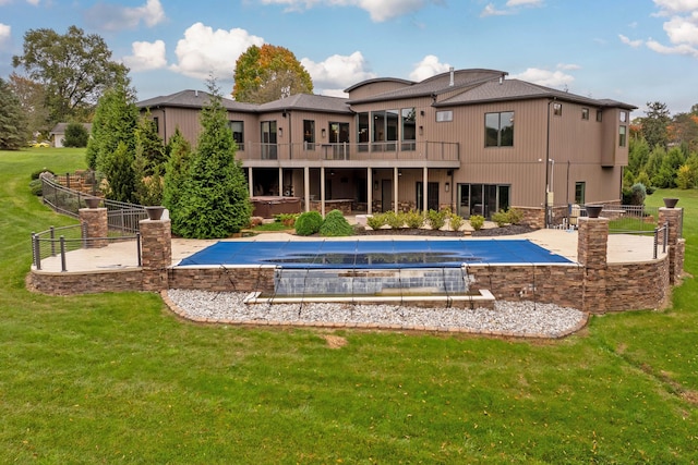 back of property featuring a lawn, a patio, and a covered pool