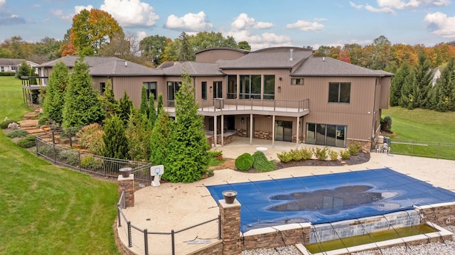 rear view of property featuring a yard, a patio, a balcony, and a covered pool