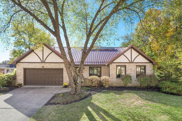 tudor home featuring a garage and a front lawn