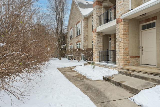 snow covered property entrance with a balcony