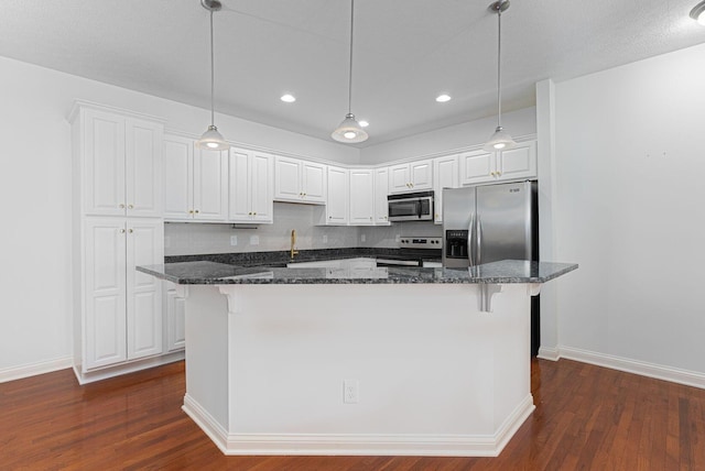 kitchen with decorative backsplash, appliances with stainless steel finishes, dark stone countertops, a center island, and white cabinetry