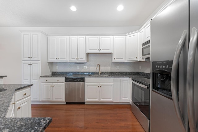 kitchen featuring white cabinets, sink, dark hardwood / wood-style floors, dark stone countertops, and stainless steel appliances