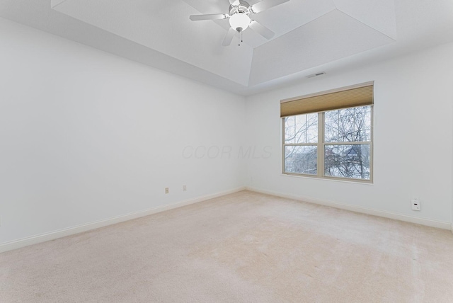 carpeted empty room with a raised ceiling and ceiling fan