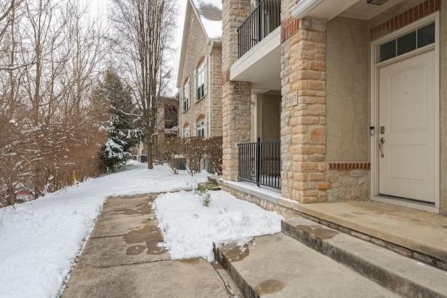 snow covered property entrance with a balcony